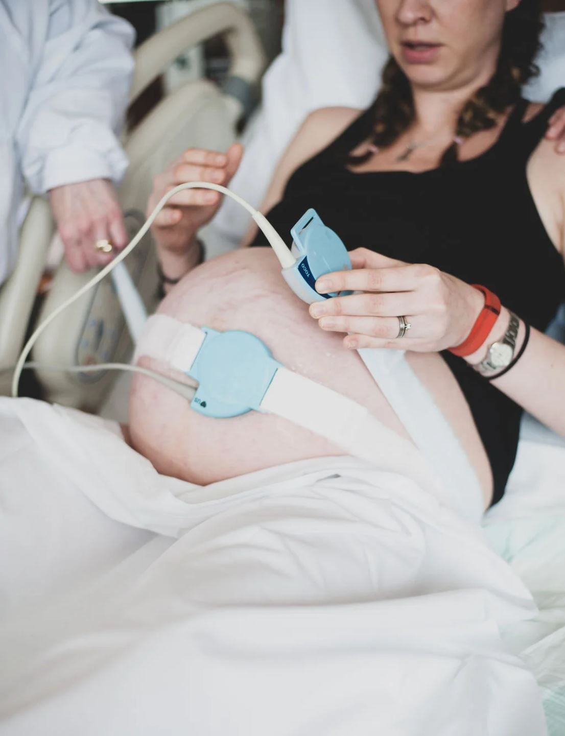 Medical monitoring devices attached to pregnant belly during labor.