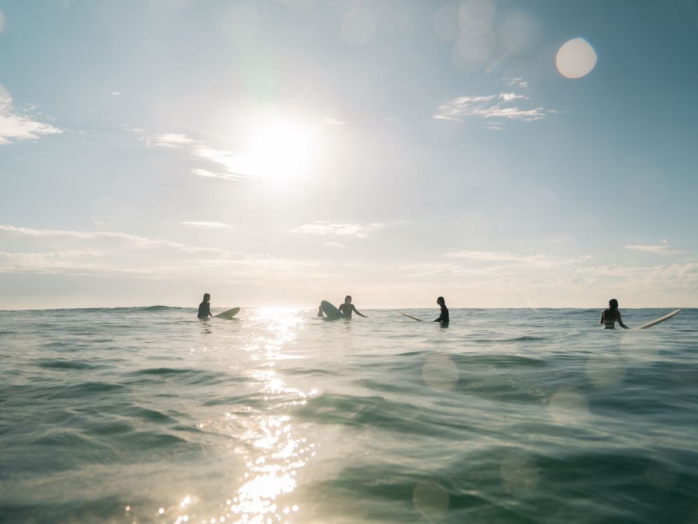 4 girls on longboards sitting and chatting waiting for waves with Sunlight Surfers social surf Dudley Newcastle NSW