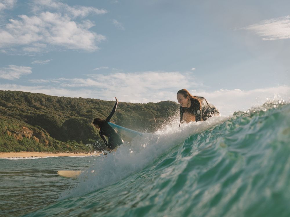 two girls miss a take off and laugh on a group social surf with Sunlight Surfers Dudley Newcastle NSW