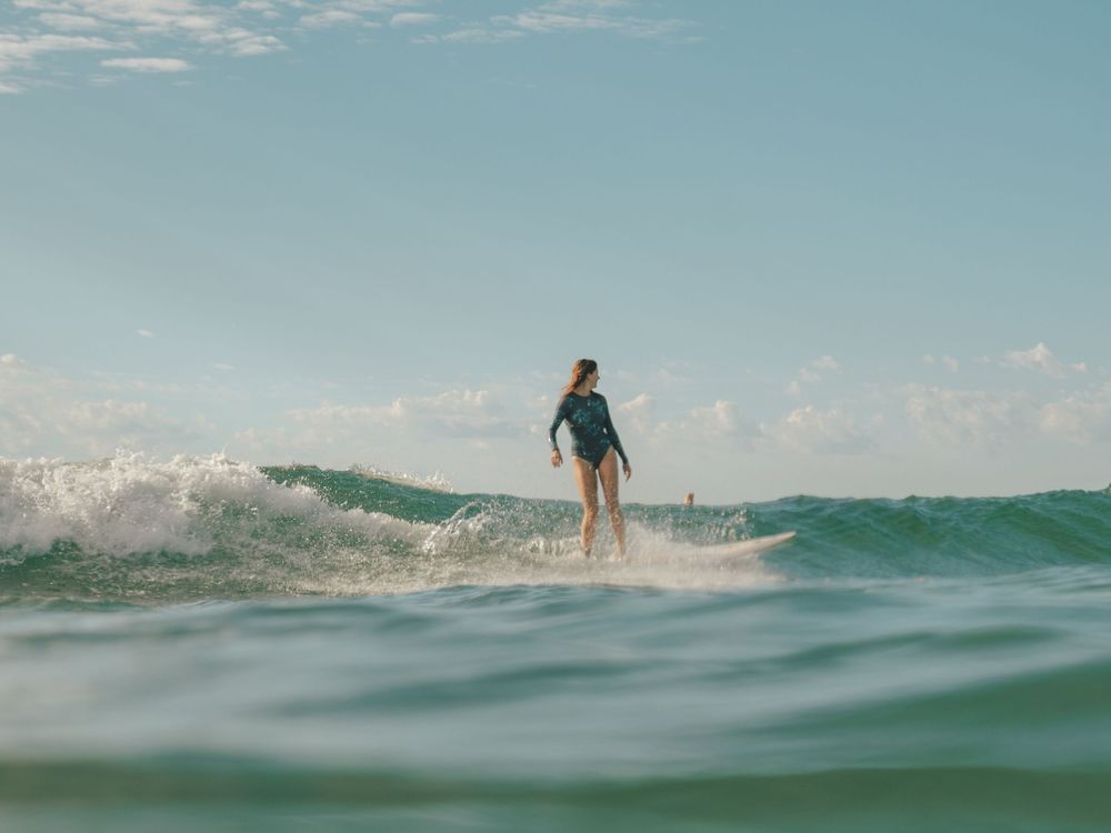 photo of a girl smiling along a wave diagonally on a group social surf with Sunlight Surfers Dudley Newcastle NSW
