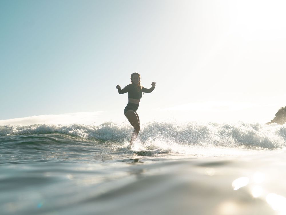 female surfer at Seal Rocks NSW near Newcastle riding a wave in the morning backlit shot