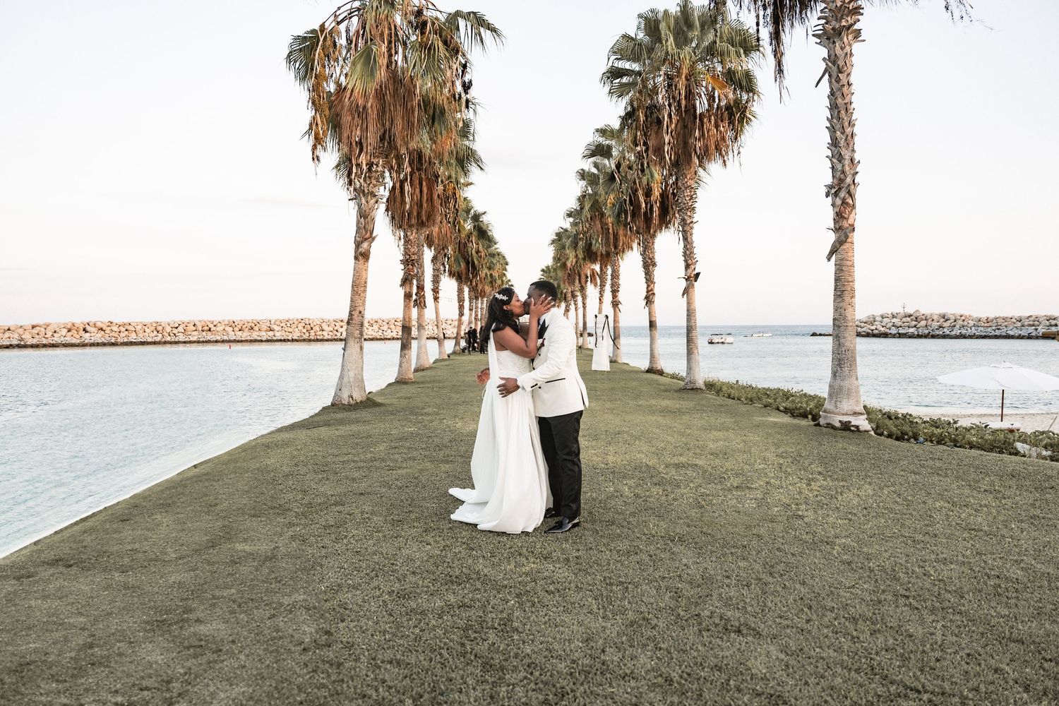 Black and white photo of a bride and groom sharing a kiss on their wedding day outdoors.