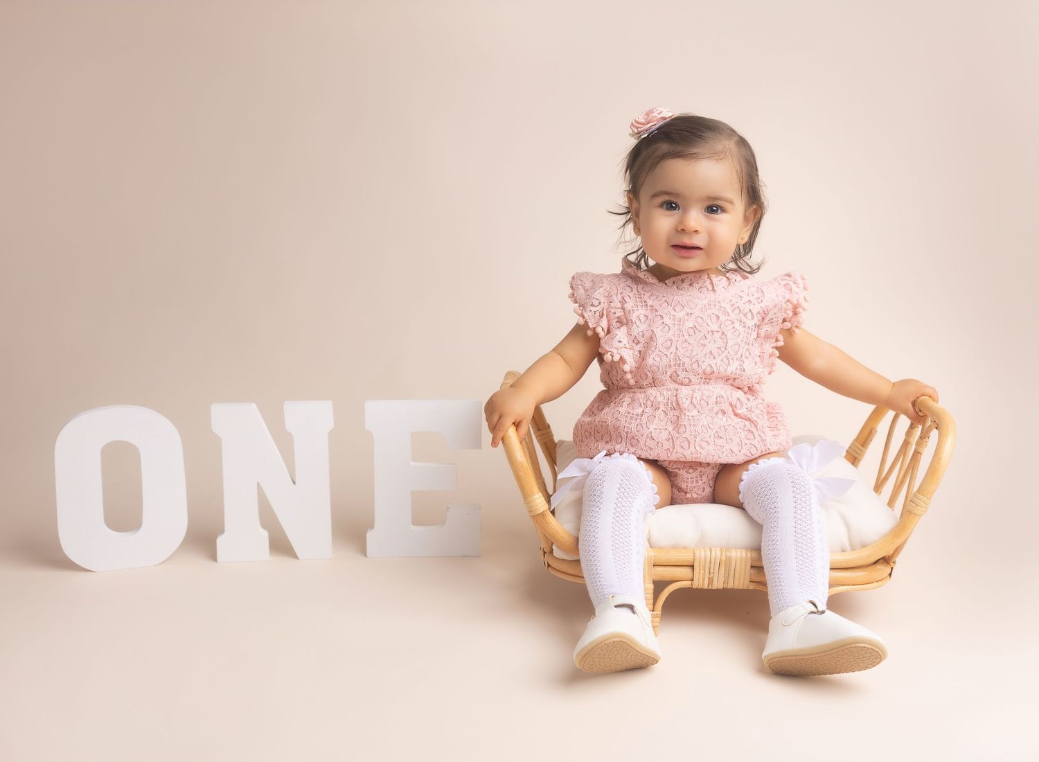 Someone holding an iced coffee drink in a photography studio with lighting equipment and pink decorations visible.