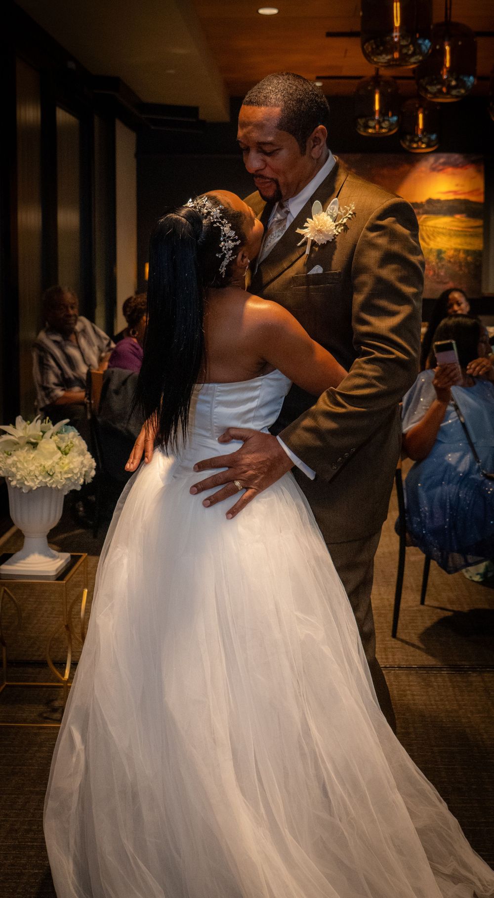 Bride and groom share an intimate embrace during wedding ceremony in warmly lit venue.
