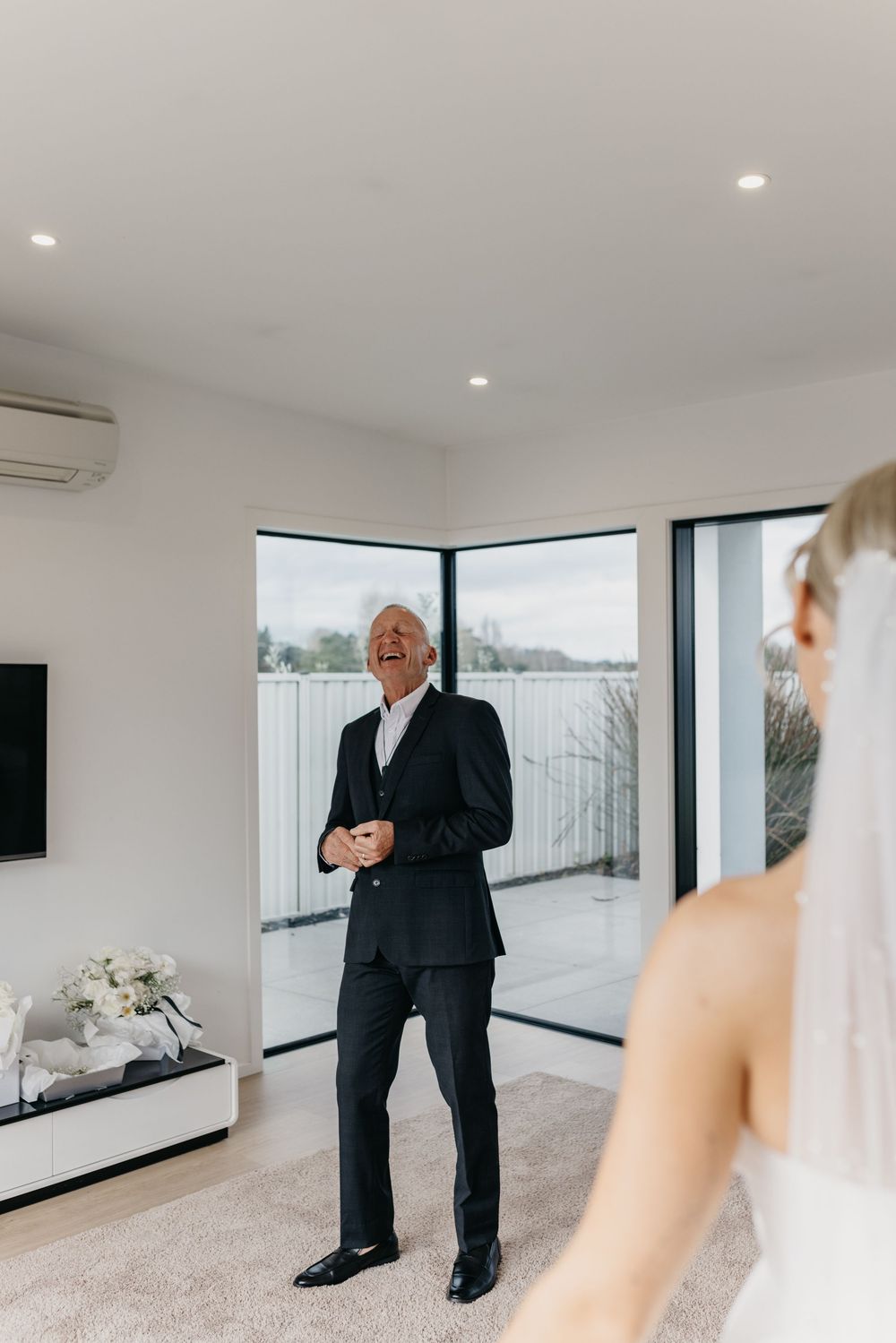 Emotional father laughing with delight as he sees his daughter in her wedding dress for the first time.