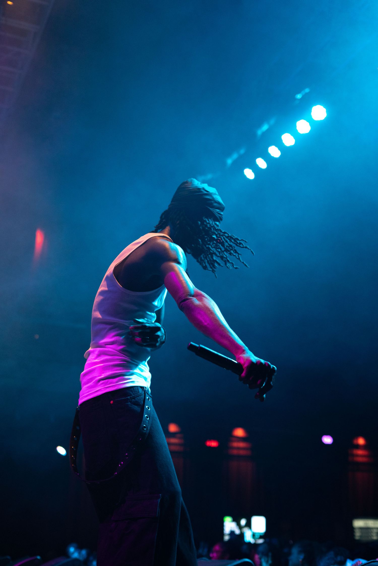Silhouetted dancer performs energetically against blue stage lighting and fog effects.