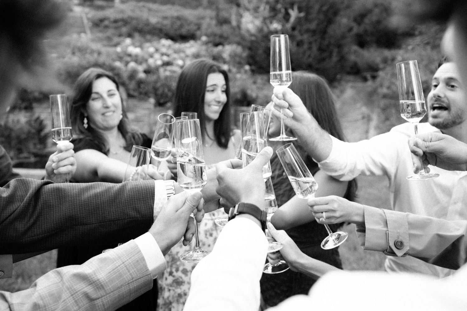 Group of friends toasting with champagne glasses outdoors in black and white photo at a celebration.