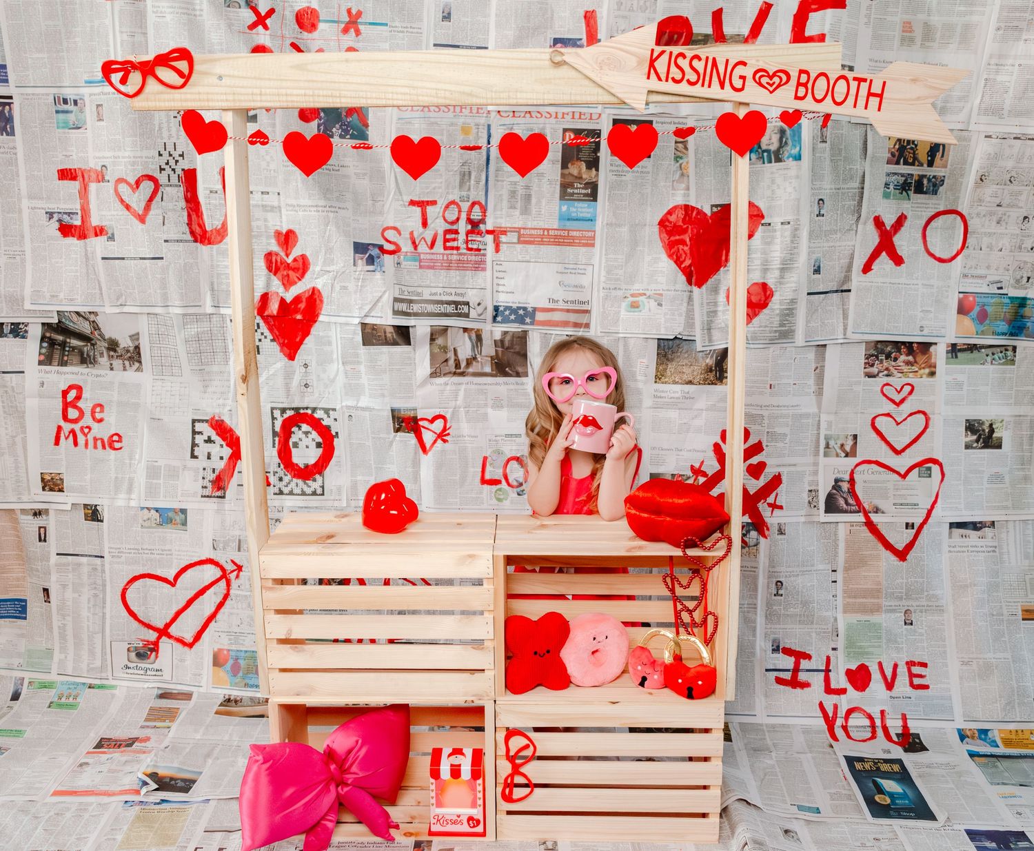 Toddler in plaid shirt at a festive hot cocoa bar stand decorated with holiday garland and bunting.