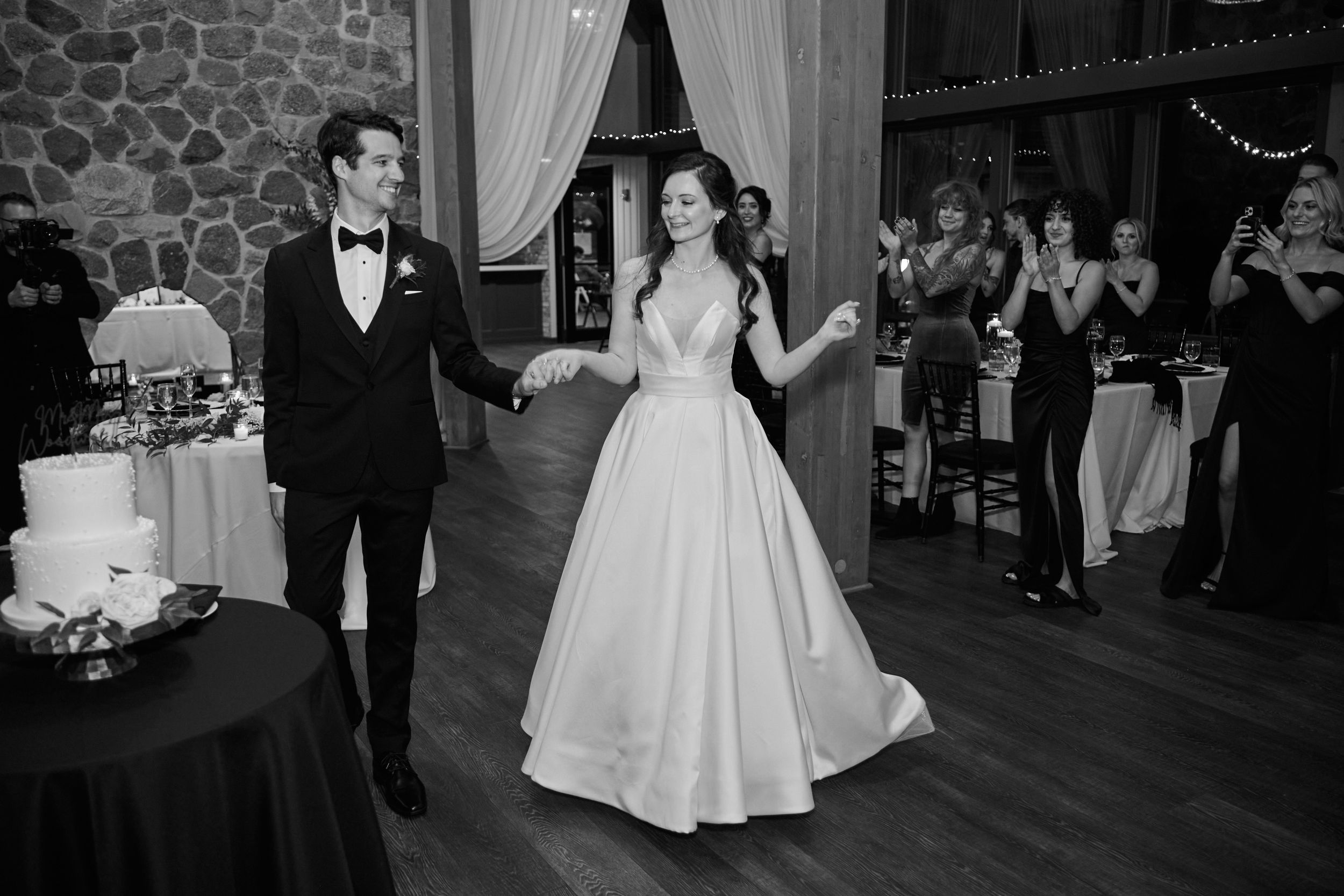Black and white photo of bride and groom sharing first dance at elegant wedding reception venue.
