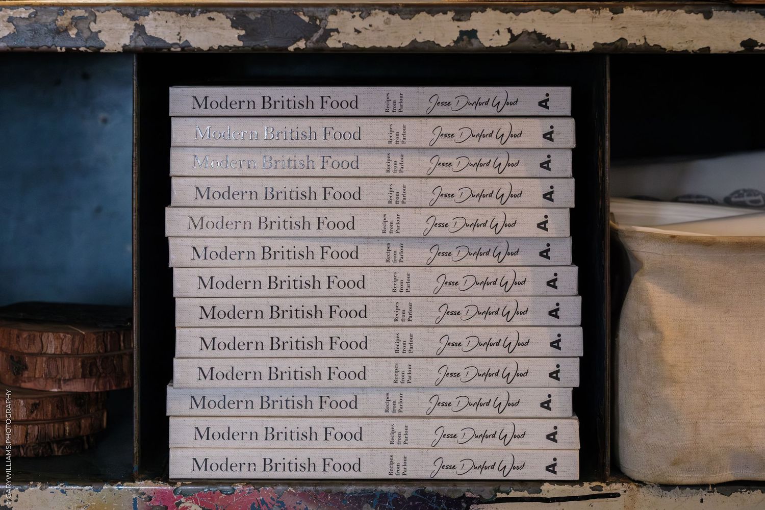Stack of Modern British Food cookbooks displayed on a shelf, showing multiple copies with elegant typography.