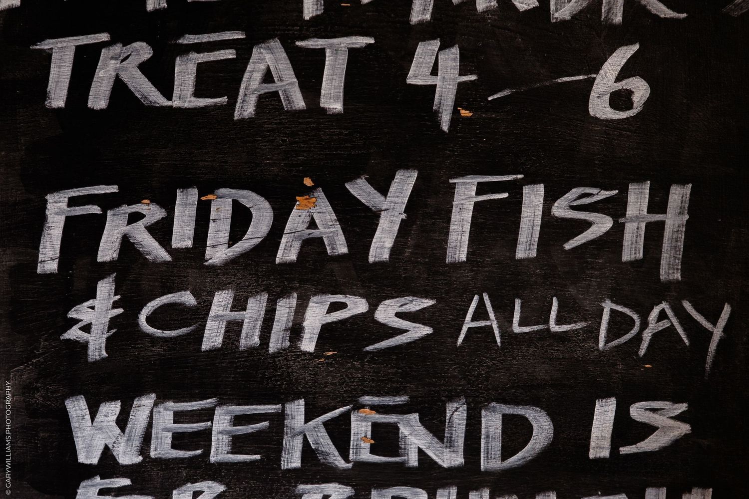 Chalkboard sign advertising Friday fish and chips all day and a treat for 4-6, weekend brunch special.