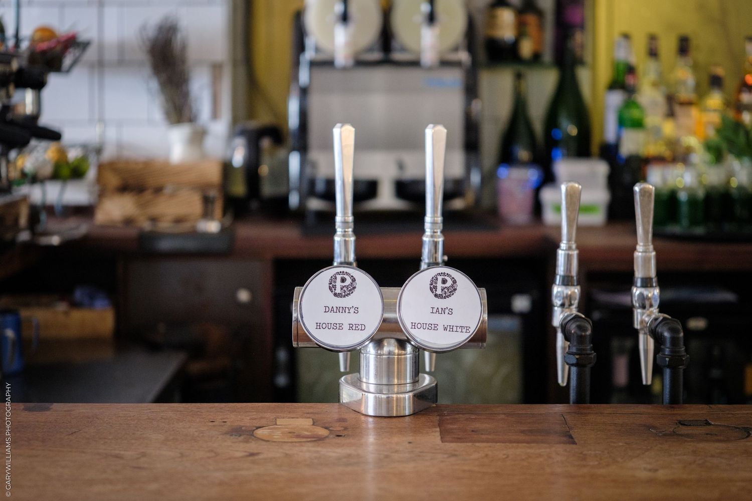 Two silver beer tap handles on a bar counter in a cozy craft brewery or pub setting.