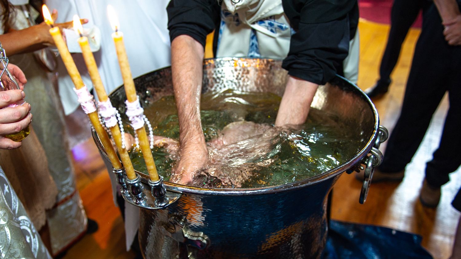 Baby being immersed in baptismal water during Orthodox Christian christening ritual.