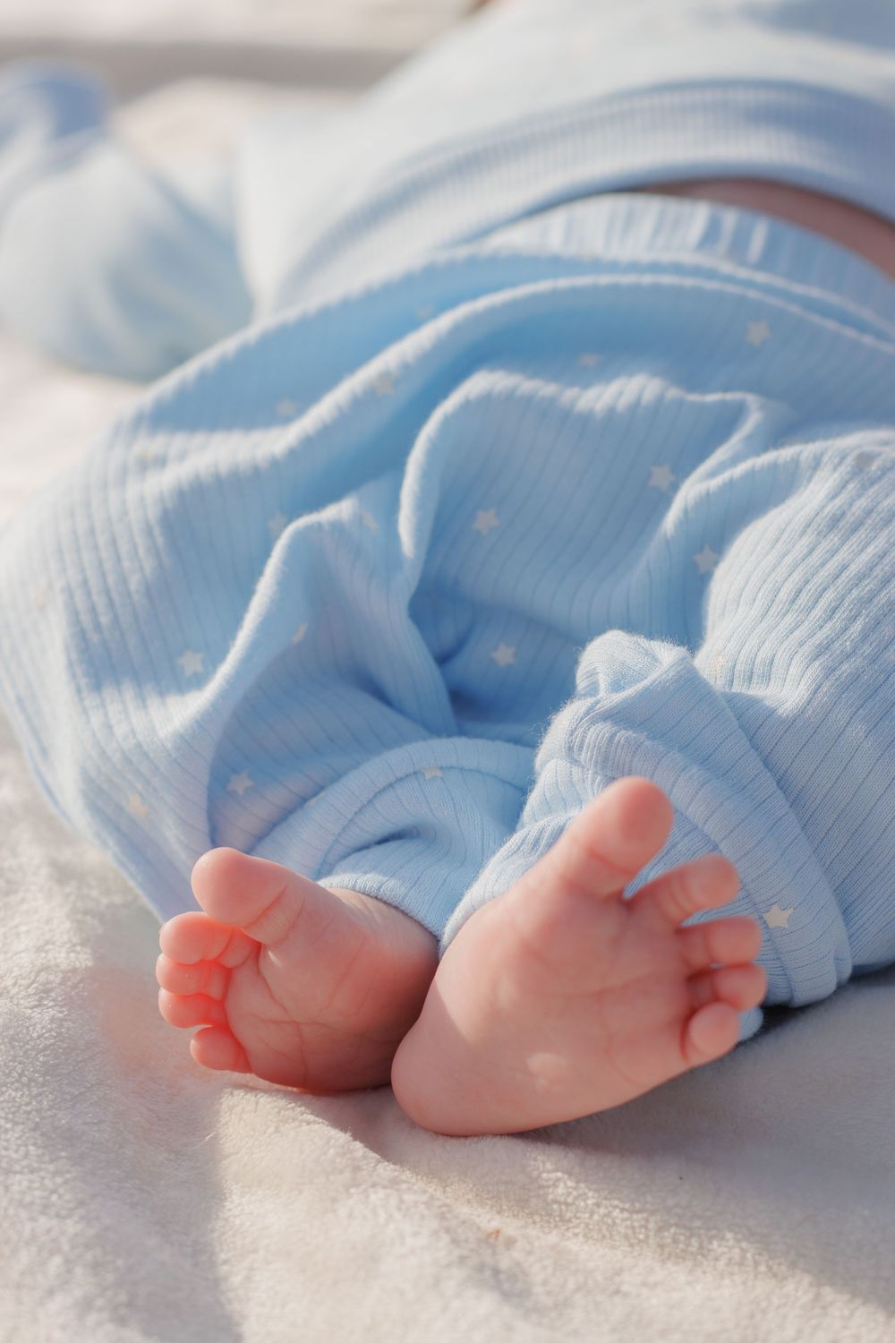 Close-up of tiny baby feet wrapped in soft blue blanket.