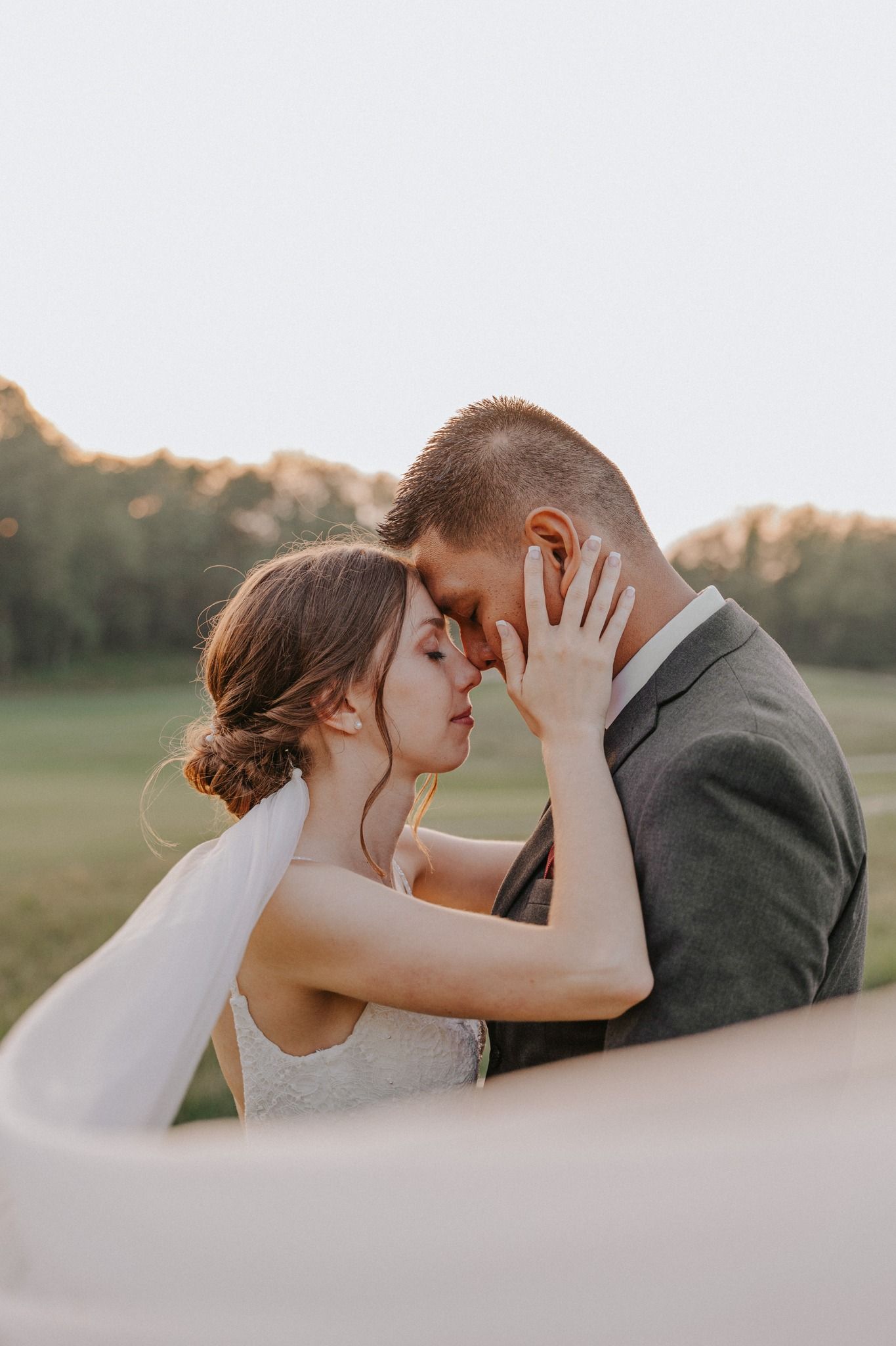 A bride and groom lie among colorful wildflowers, sharing a romantic moment in a dreamy wedding photo.