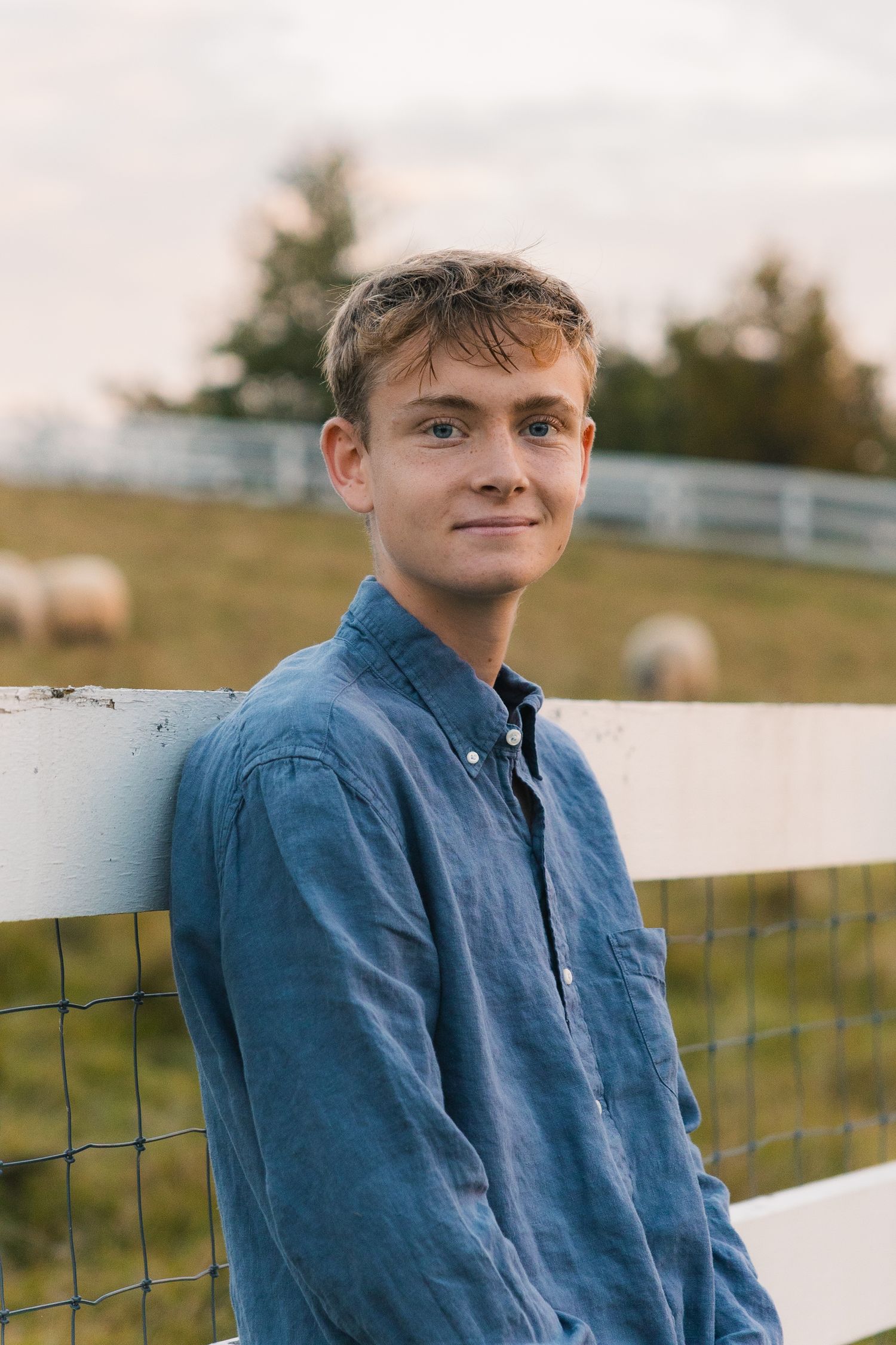 madison wi professional yearbook photos high school senior photographer waste up headshot boy posing against fence epic verona sheep farm