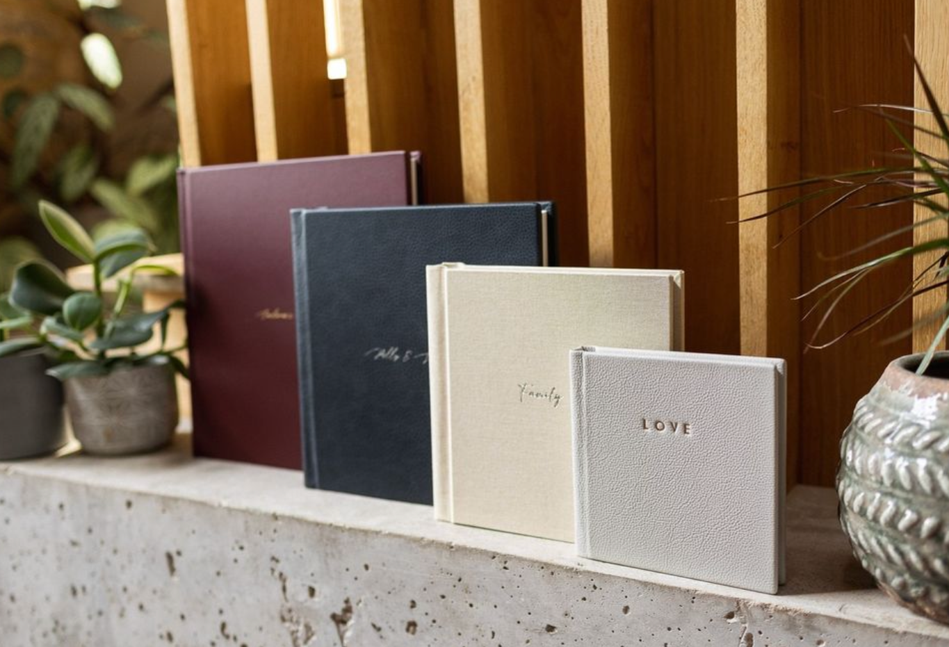 Row of elegant wedding photo albums displayed on a concrete ledge.