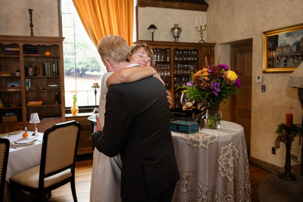 Newlywed couple sharing loving embrace near floral arrangement in charming vintage interior.