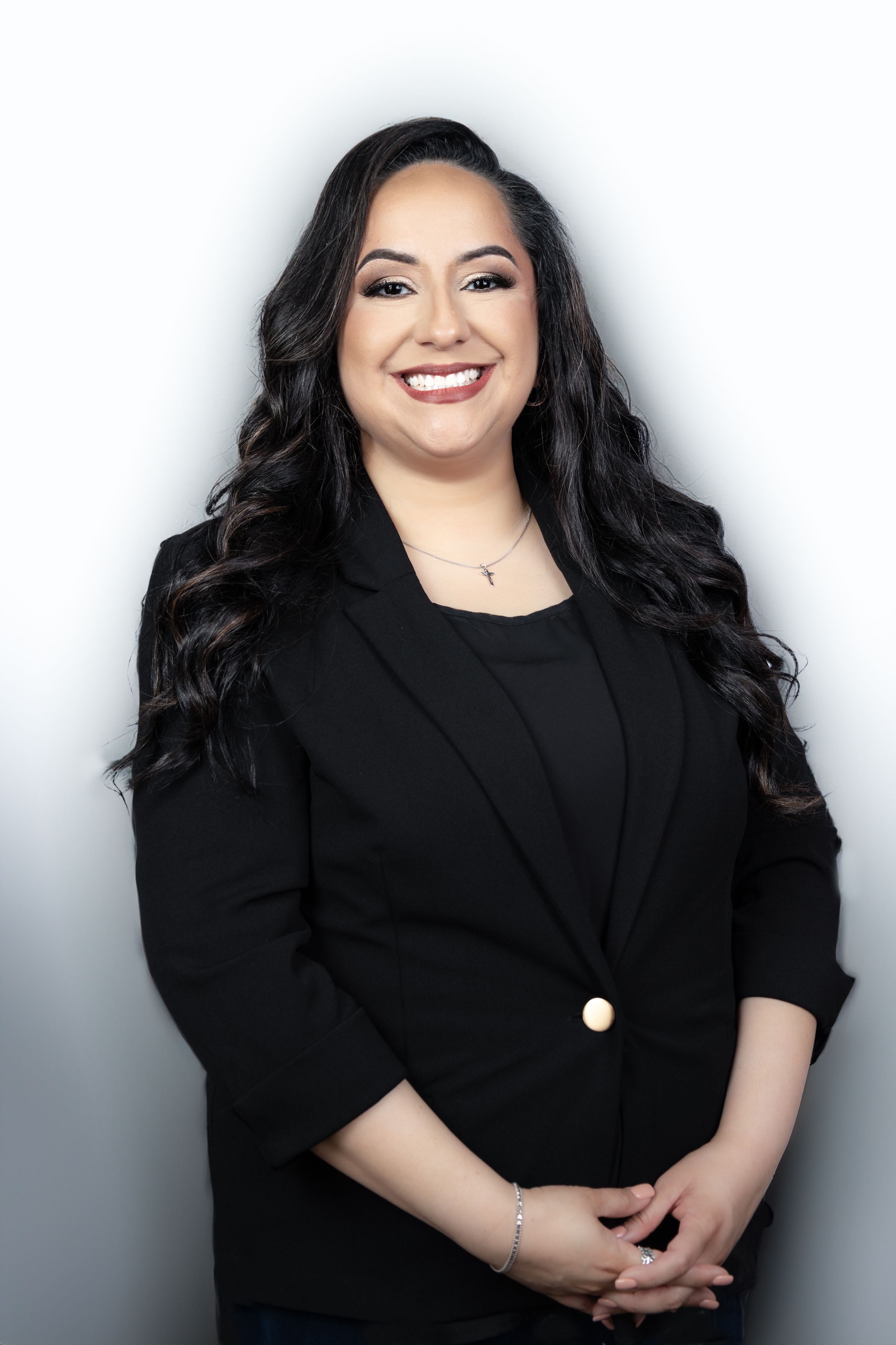 Professional woman in black blazer smiling confidently against white background for business portrait photo.