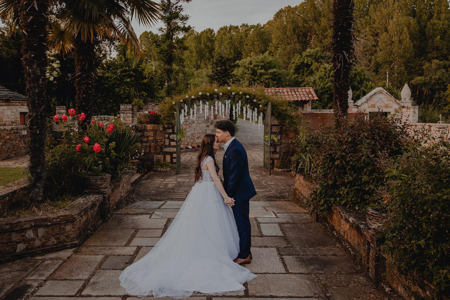 A romantic garden pathway lined with stone walls and greenery during a wedding shoot.