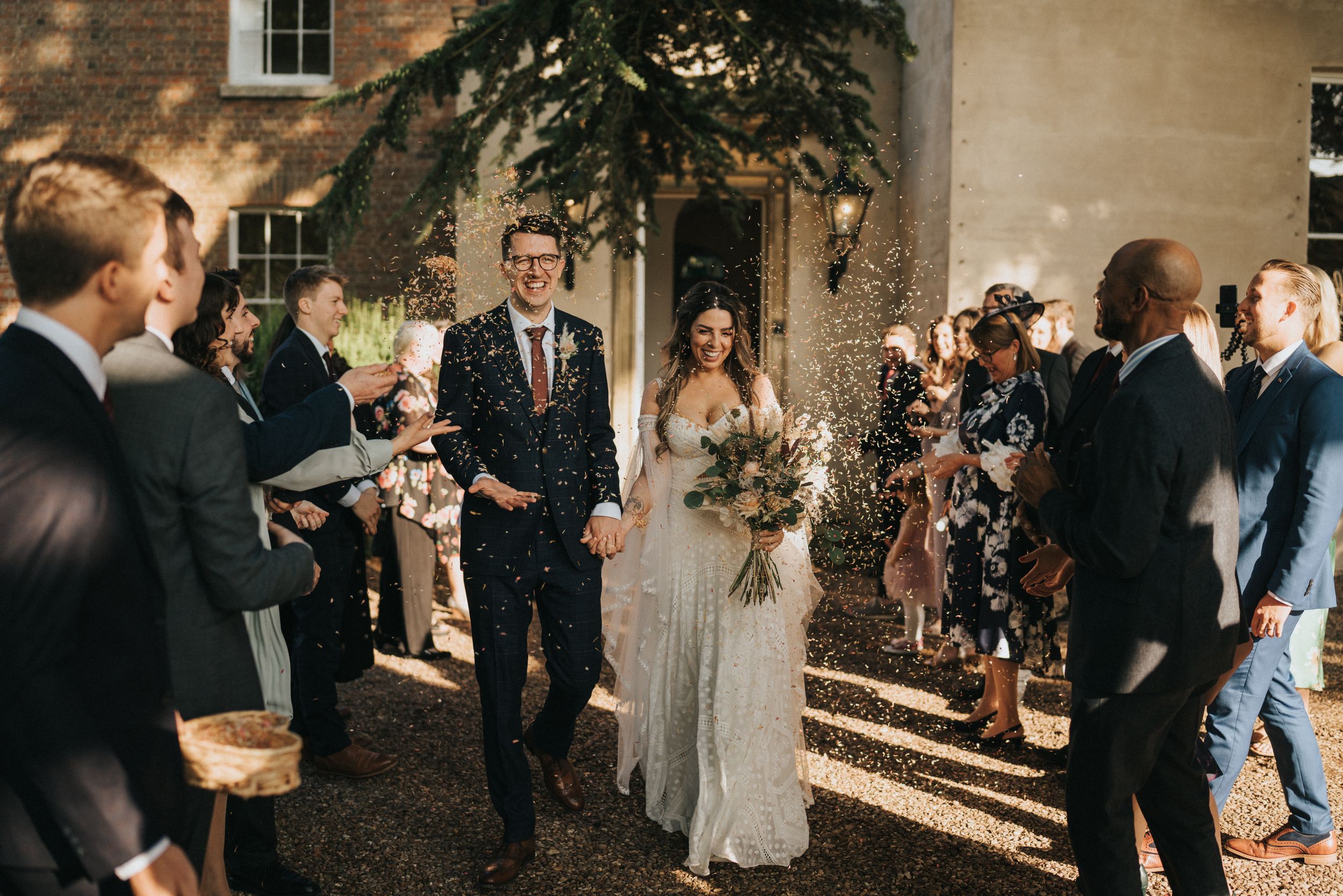 Wedding guests celebrating with dancing and mingling in the courtyard of a historic brick building at sunset at Aswarby Rectory.