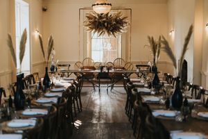 Elegant reception hall with rustic decor featuring greenery and minimalist table settings in warm natural light at Aswarby Rectory.