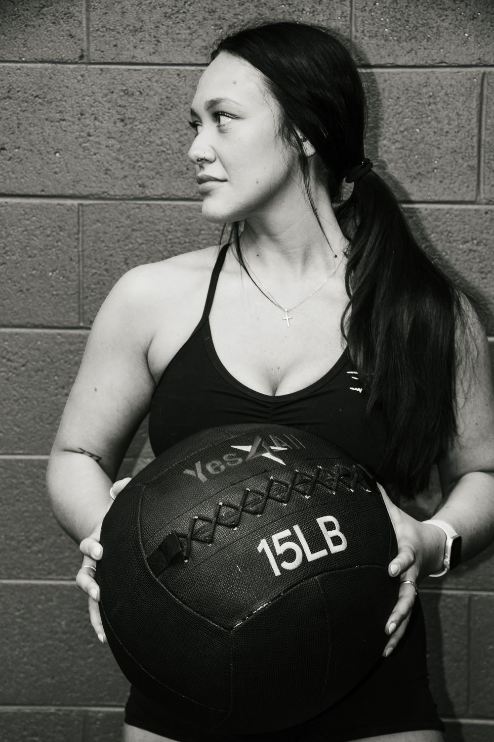 Woman holding a 15lb medicine ball, looking confidently to the side
