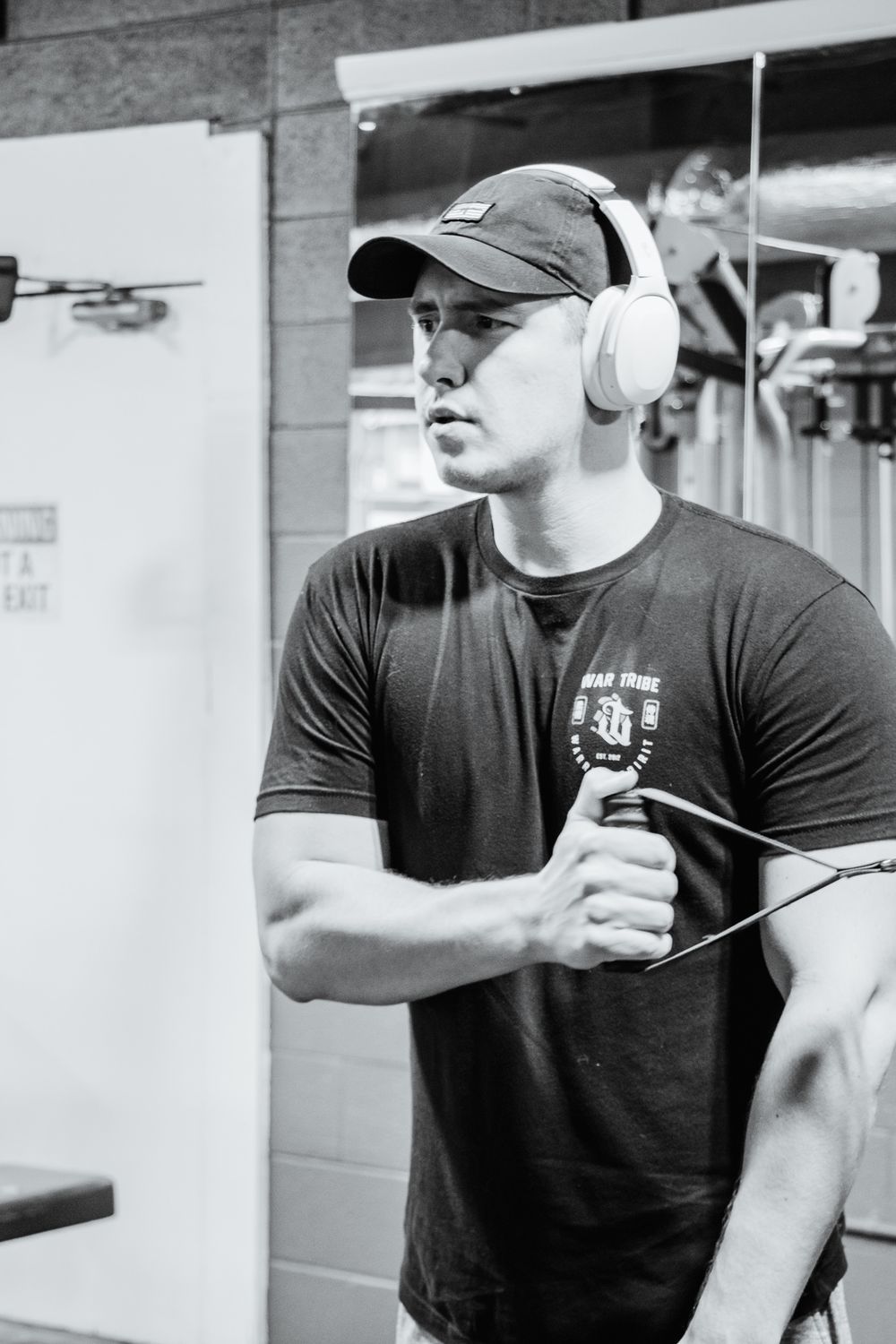 Man in headphones doing a single-arm cable row at the gym.