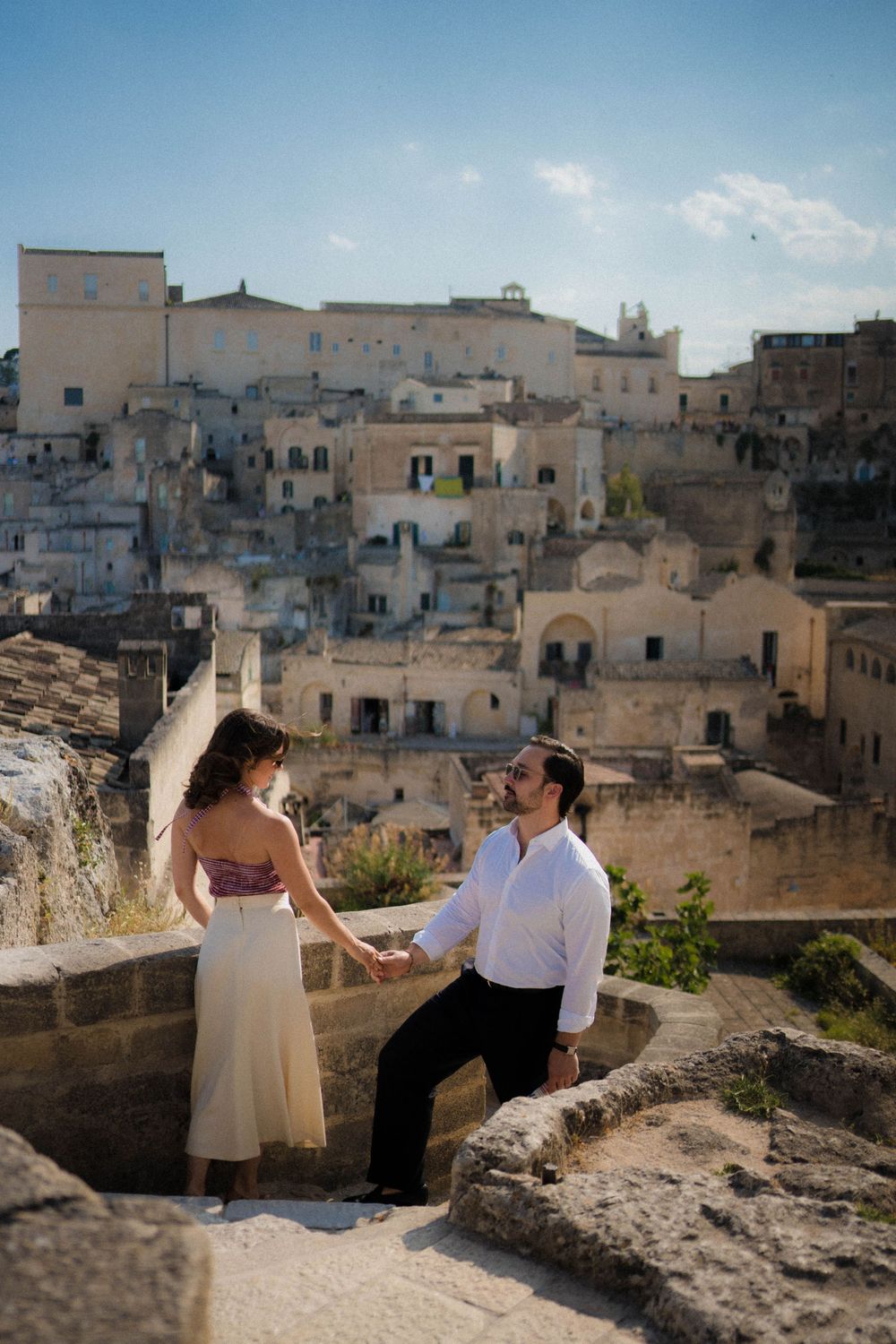 Historic stone buildings and architecture in an ancient city with couple sitting together on a terrace overlooking rooftops.