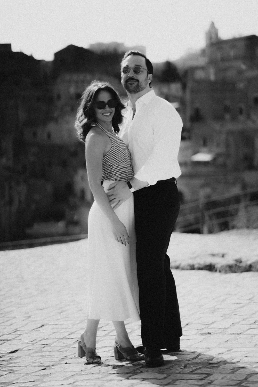A couple poses together in a black and white romantic photo sequence on a textured white surface.