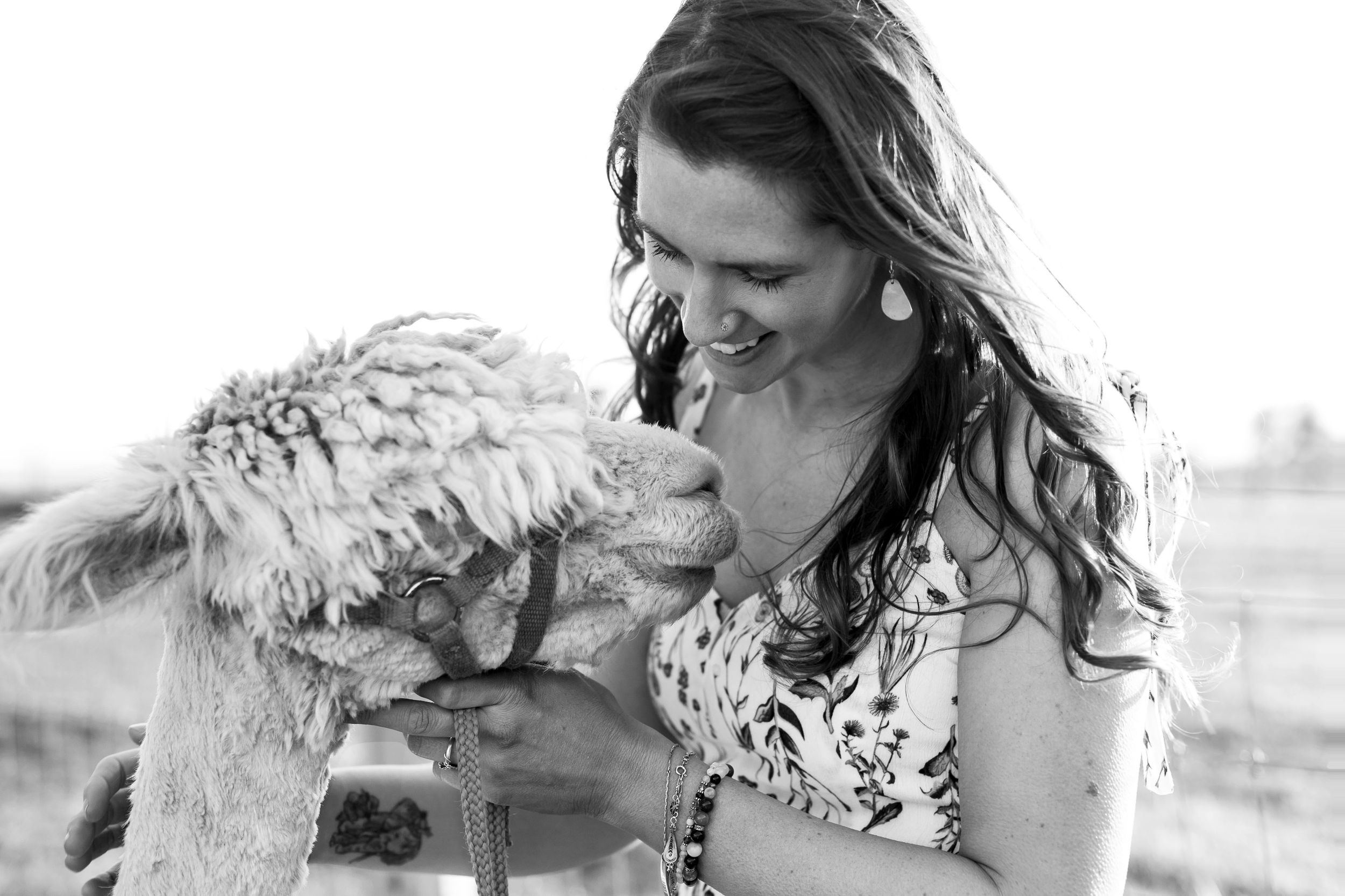 Woman smiling down at an alpaca.