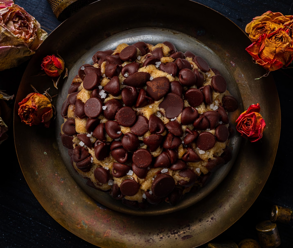 Chocolate chip cookie loaded with dark chocolate chips on rustic metal plate.
