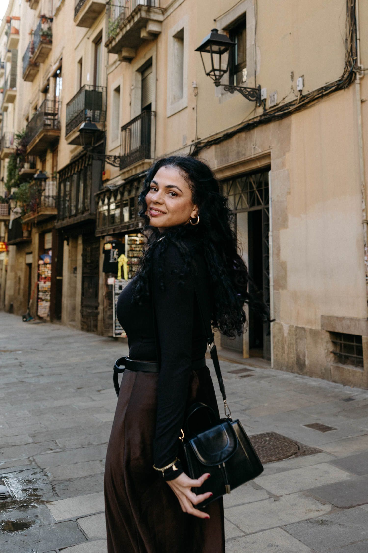 Narrow cobblestone street lined with historic buildings and traditional lampposts in Barcelona.