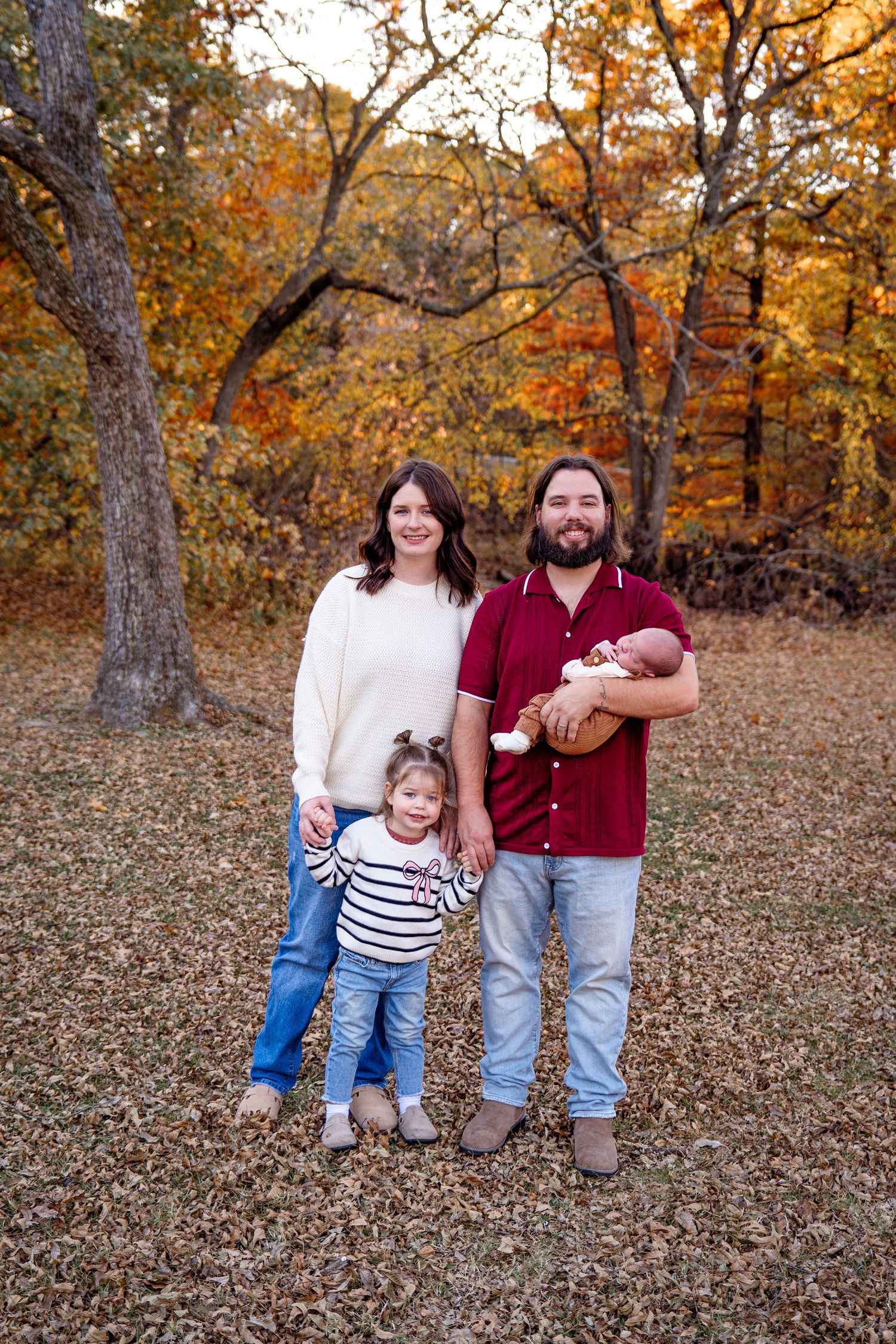 Family portrait with fall foliage and autumn colors in background.