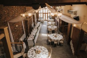 Round dining tables elegantly arranged in a rustic brick-walled venue at Hall Farm - image captured by Grimsby photographers.