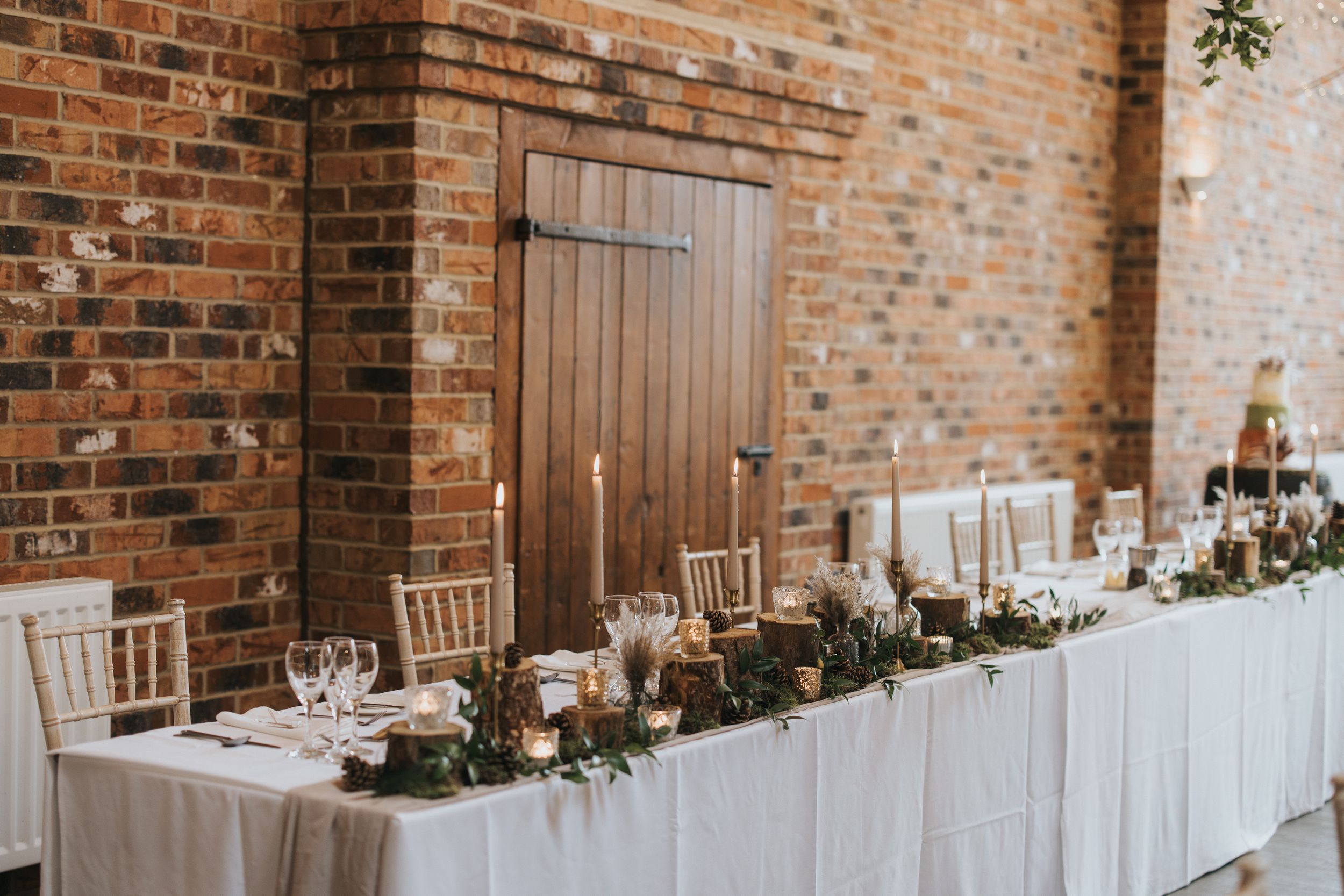 Elegant wedding head table setup against a rustic brick wall at Hall Farm - image captured by Grimsby photographers.
