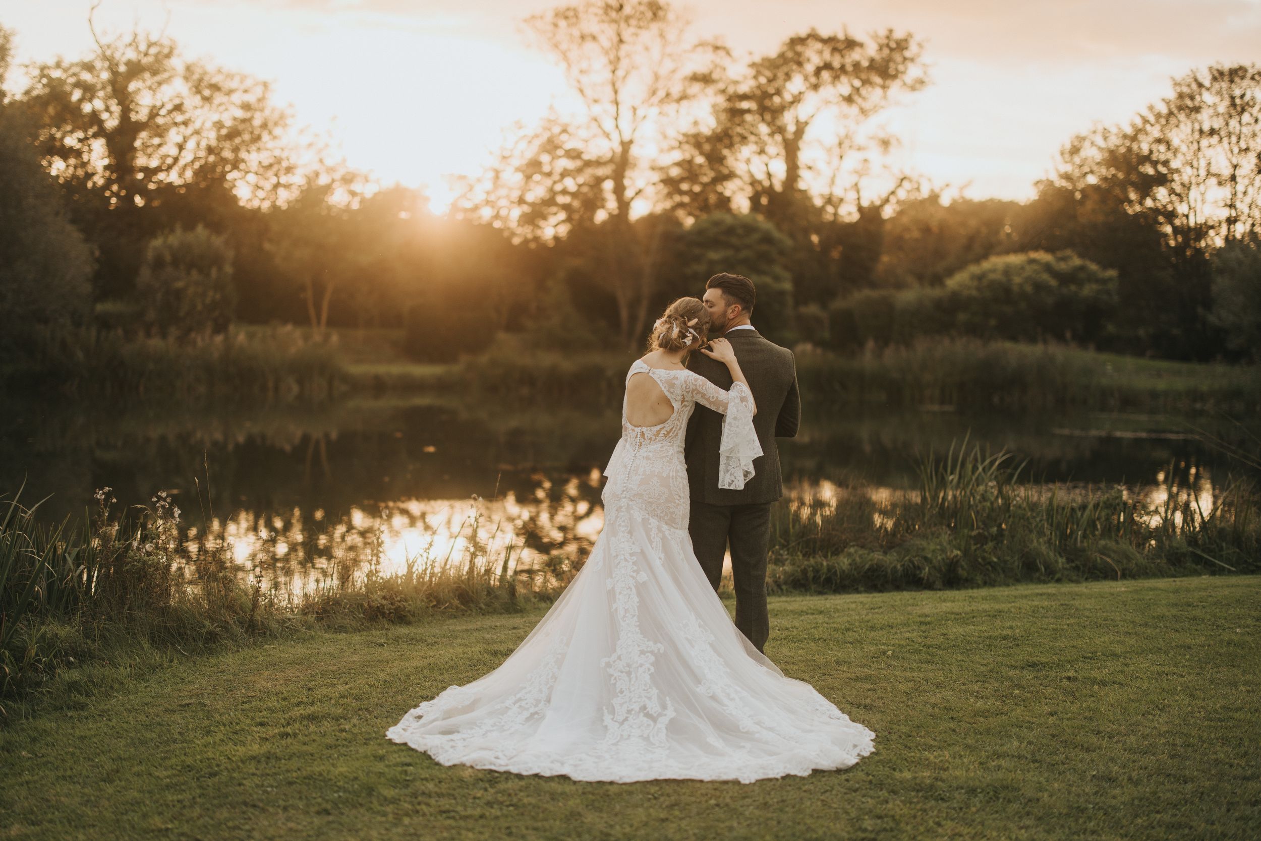 A romantic couple embraces during golden hour sunset by a serene pond at Hall Farm - image captured by Grimsby photographers.