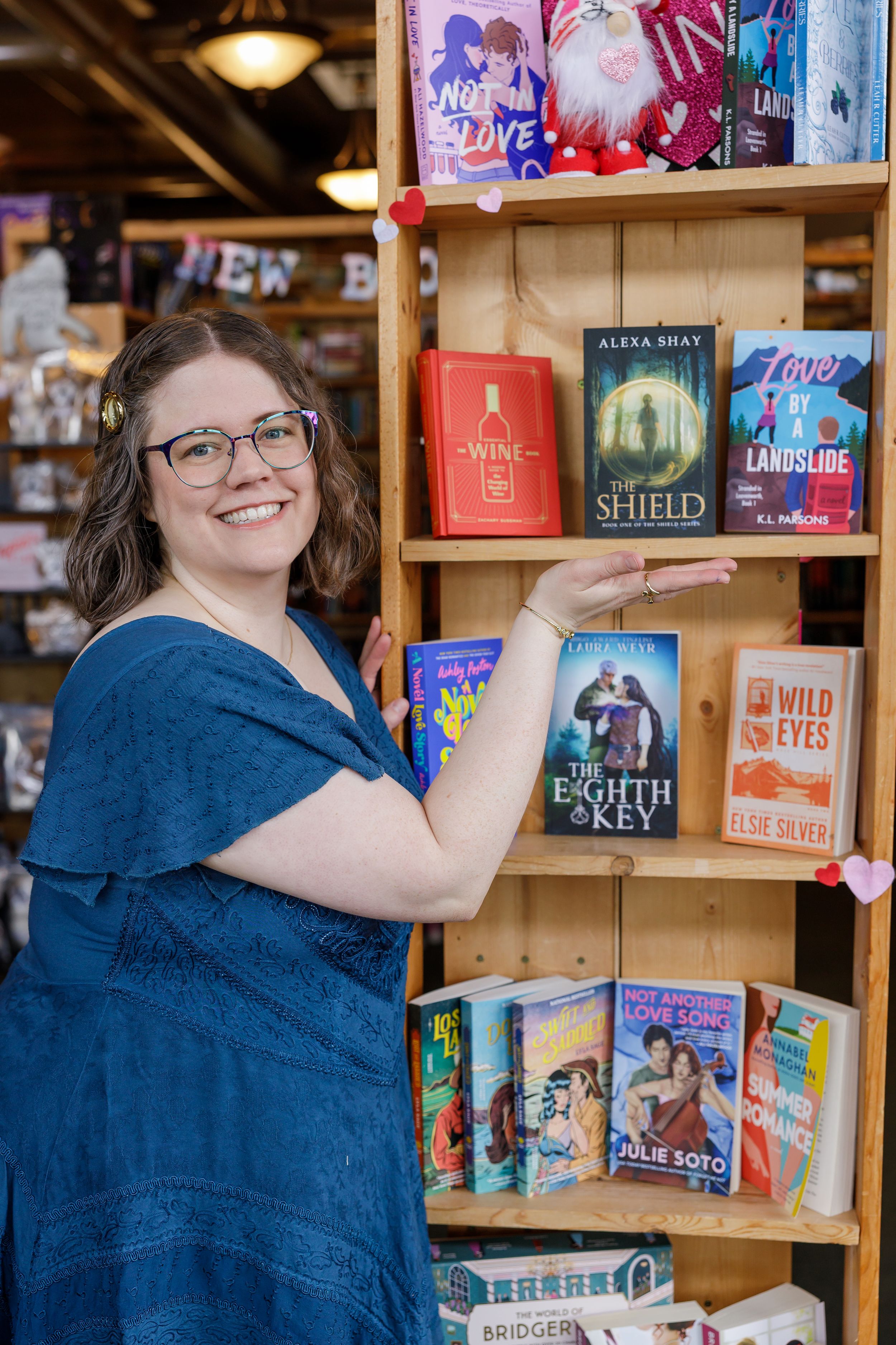 indie book author Alexa Shay author signing event in Seattle, WA bookstore lifestyle headshot standing pointing to book smiling