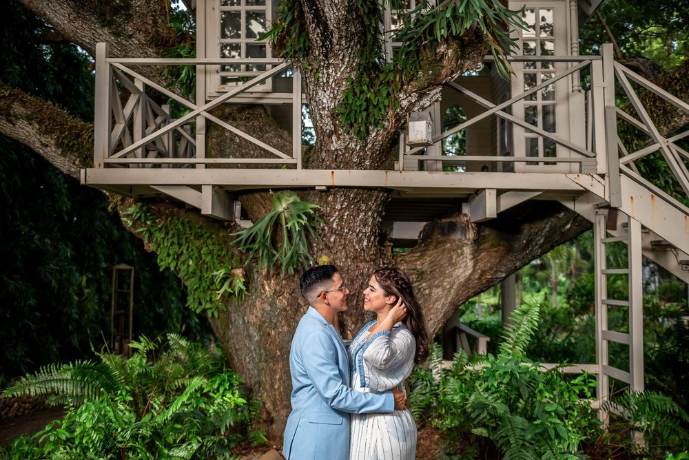 A couple shares intimate romantic moments in a garden setting with rustic white architectural elements and lush greenery.