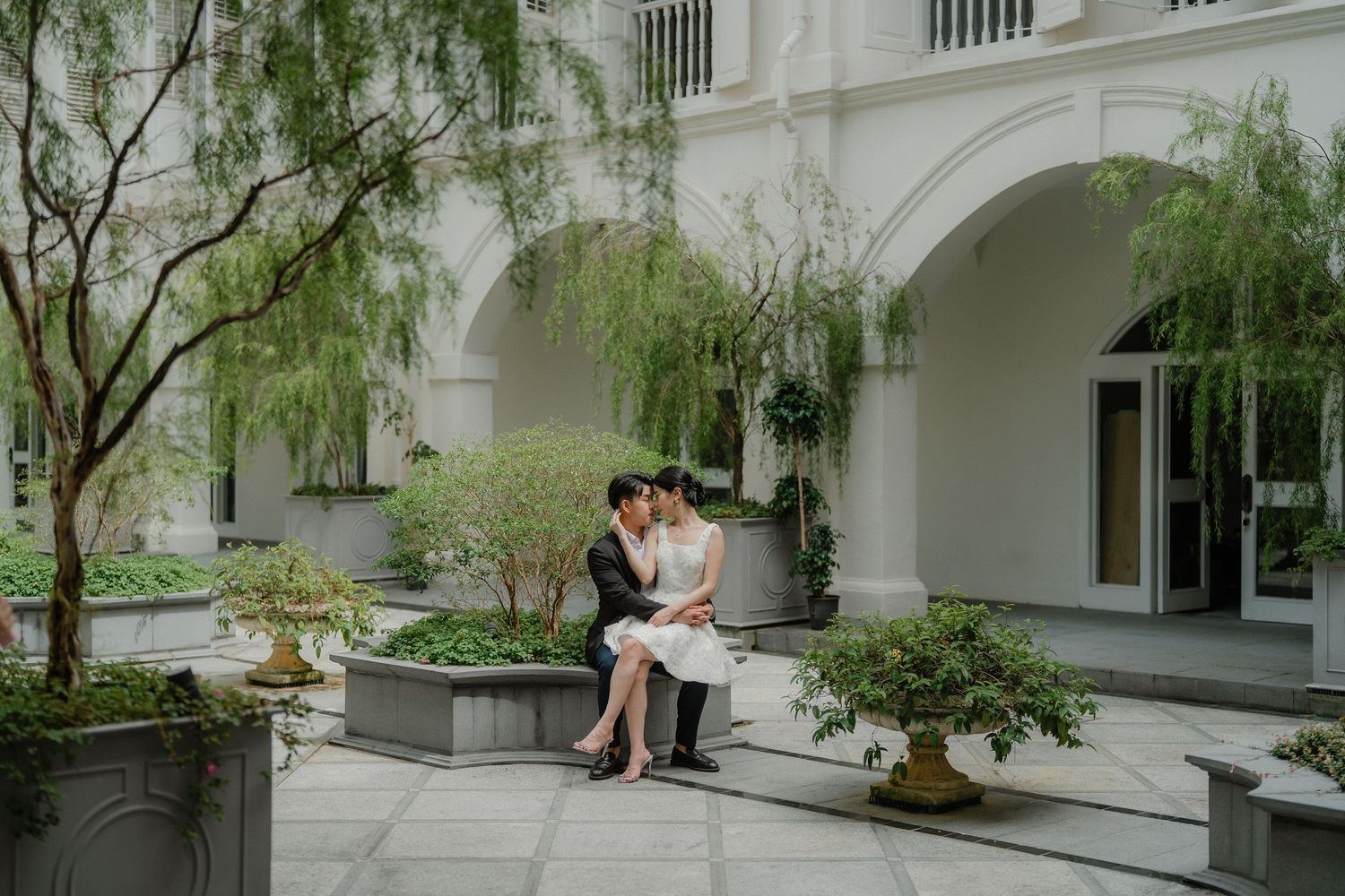 Wedding photography session captured in a serene white courtyard with cascading greenery and arches.