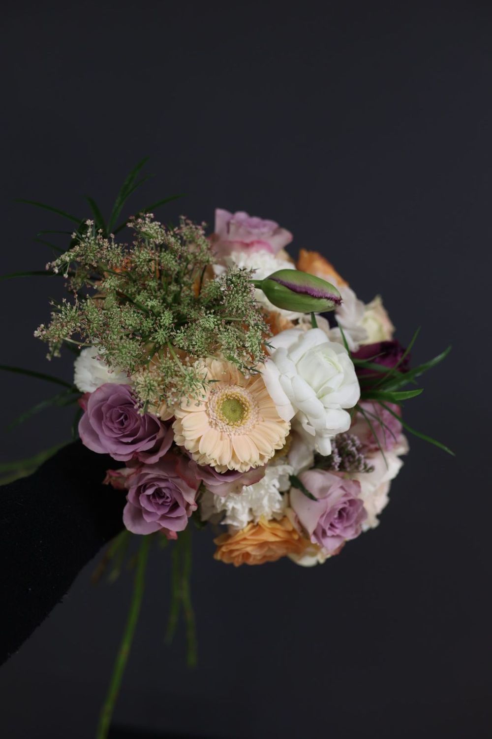 Soft romantic bouquet with mauve roses, gerbera daisy, white peony, and Queen Anne's lace accents.
