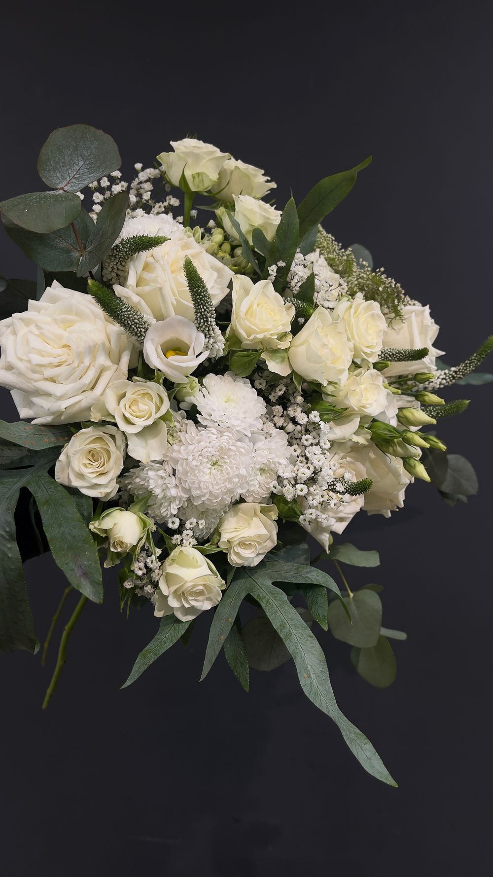 Elegant all-white bridal bouquet with roses, lisianthus, chrysanthemums, baby's breath, and eucalyptus.