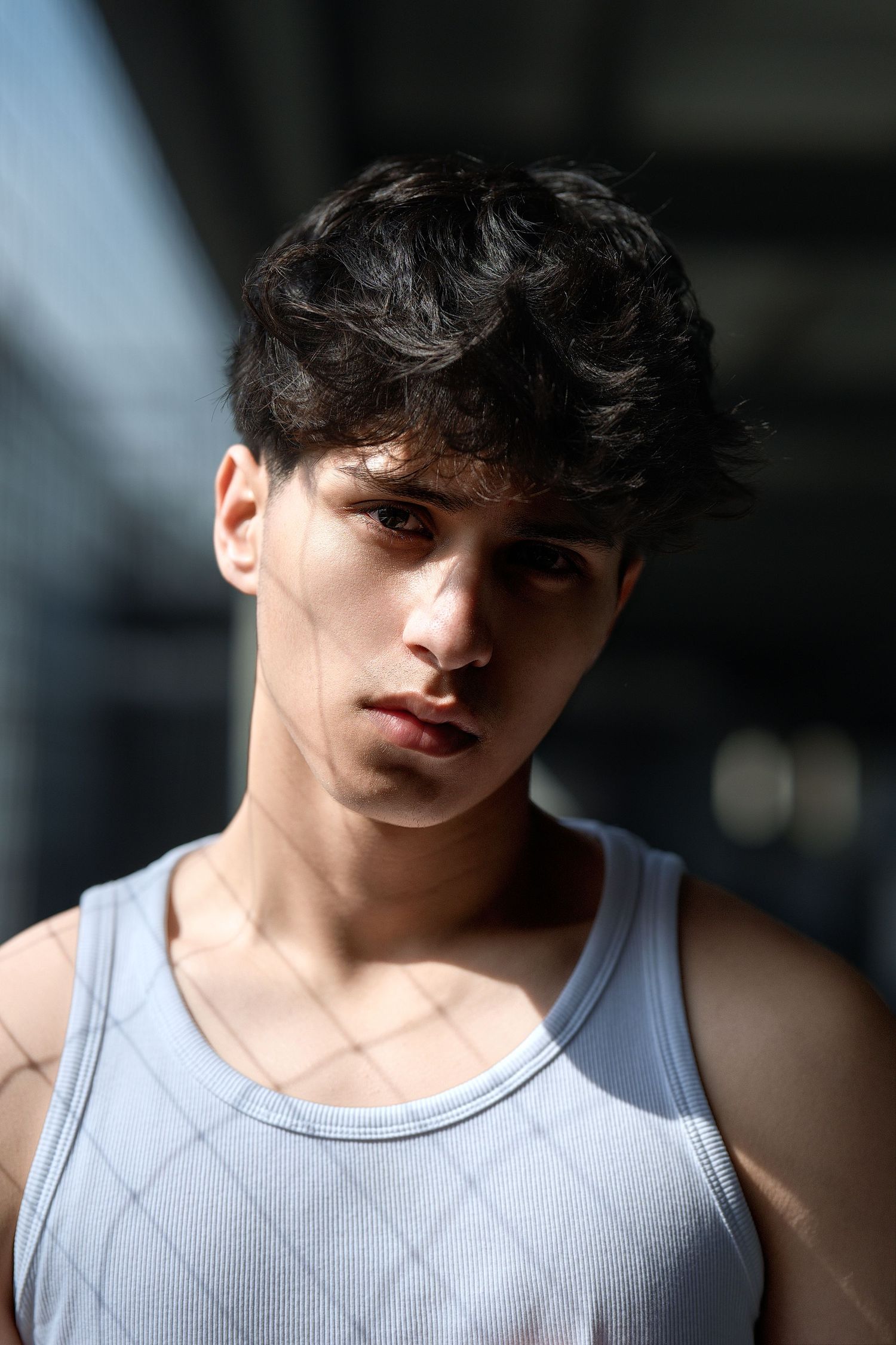 Figure in white tank top shown in varying artistic angles with dramatic lighting and shadows cast against dark backdrop.