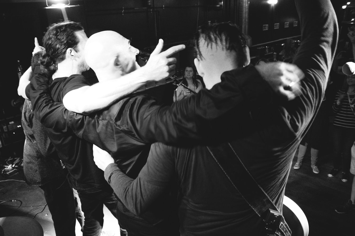 Black and white photo showing energetic dancers performing dynamic moves in a dark venue.