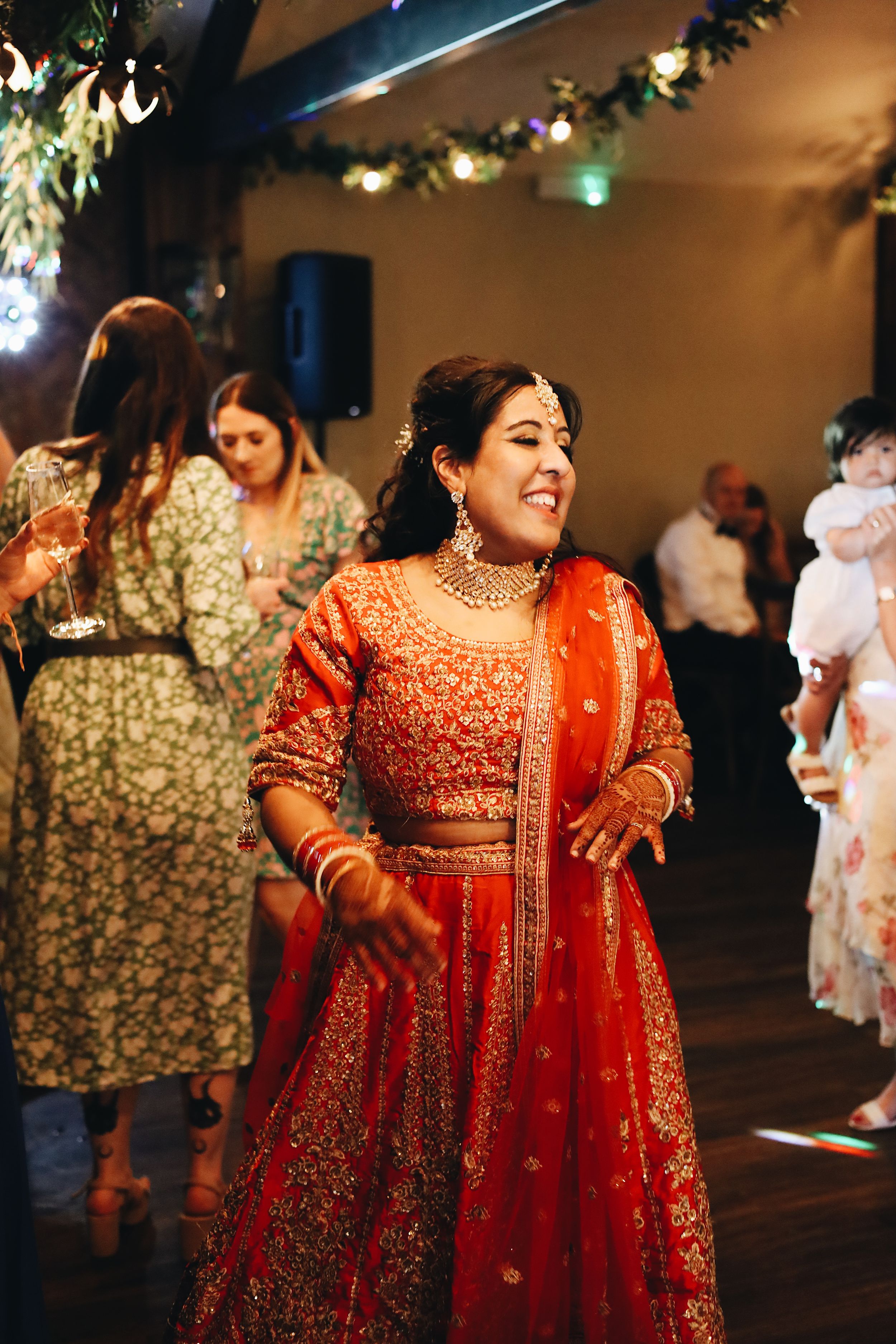 Woman dancing in ornate red and gold traditional Indian wedding attire.