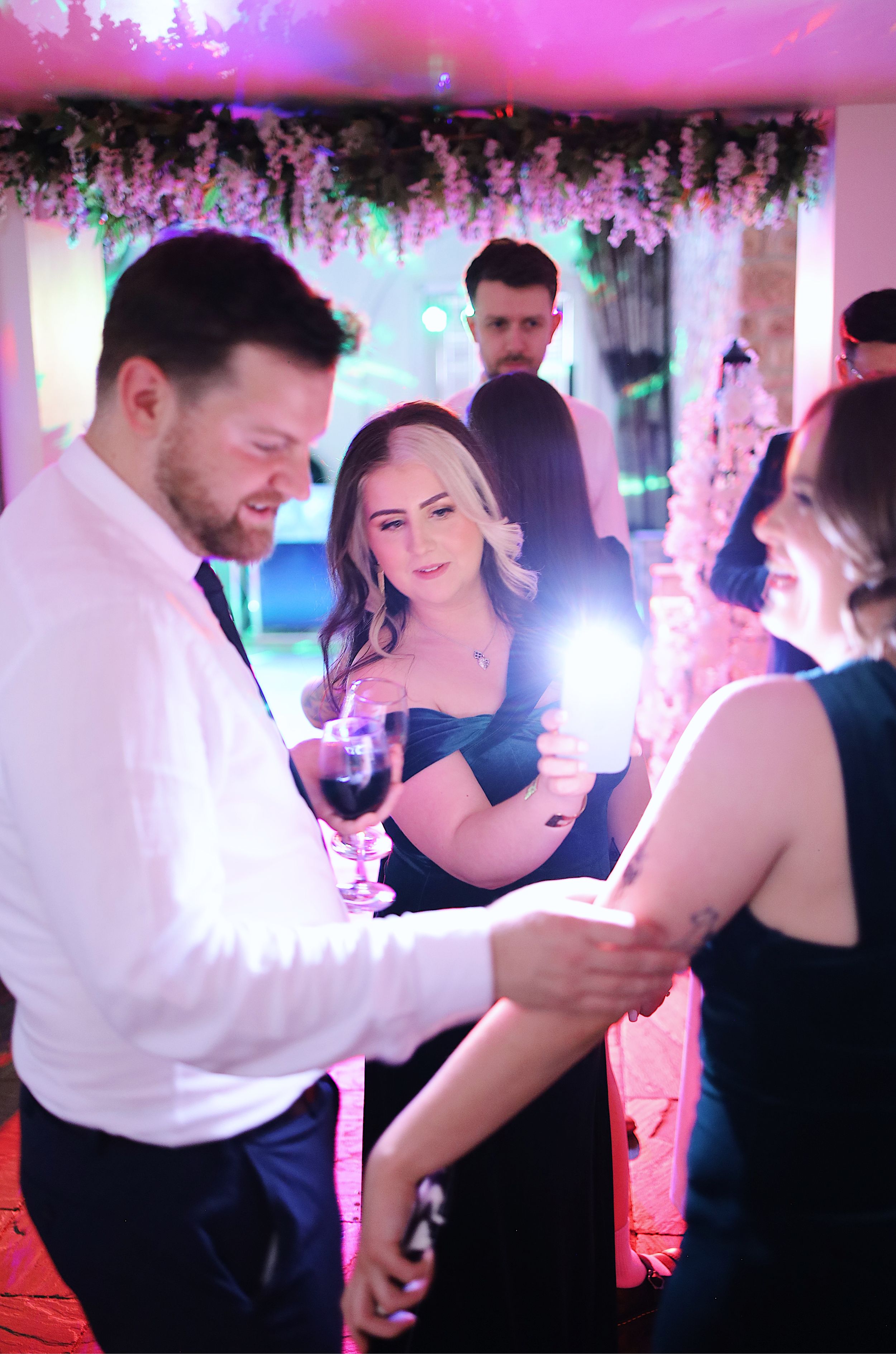A couple dances together under pink and purple lighting at a wedding reception.