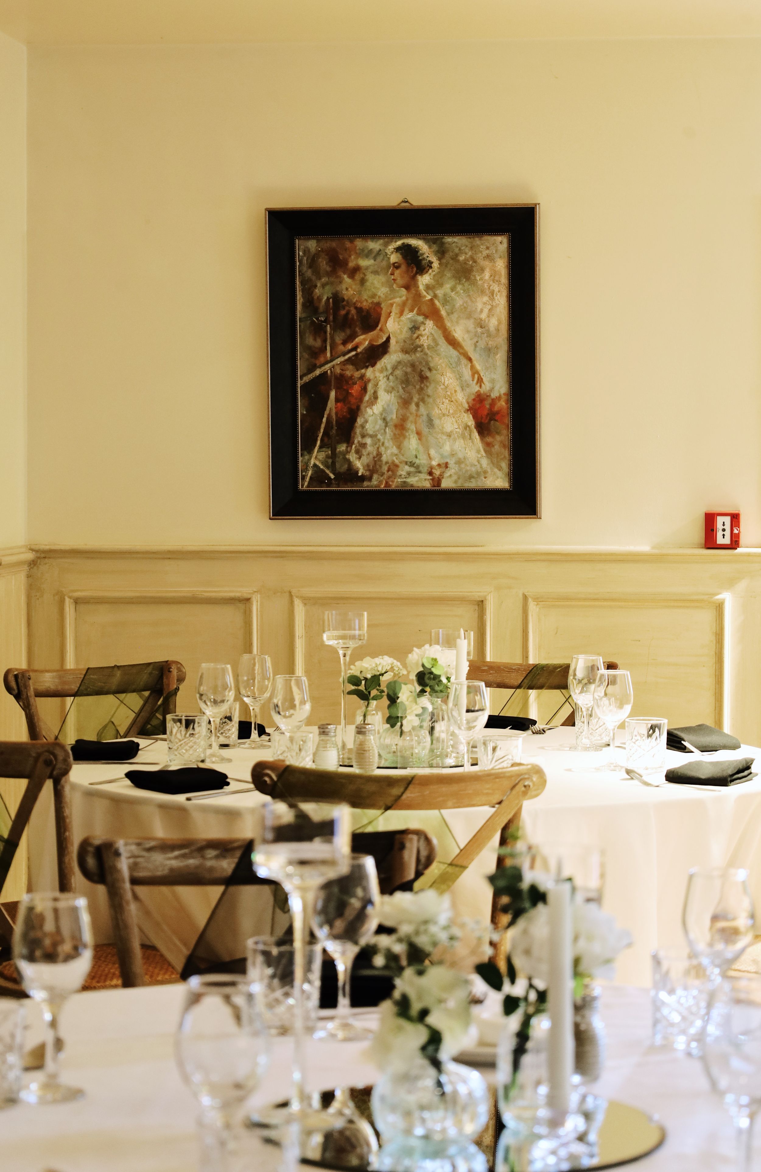 Elegant wedding reception table setting with framed artwork and wine glasses in a bright dining room.