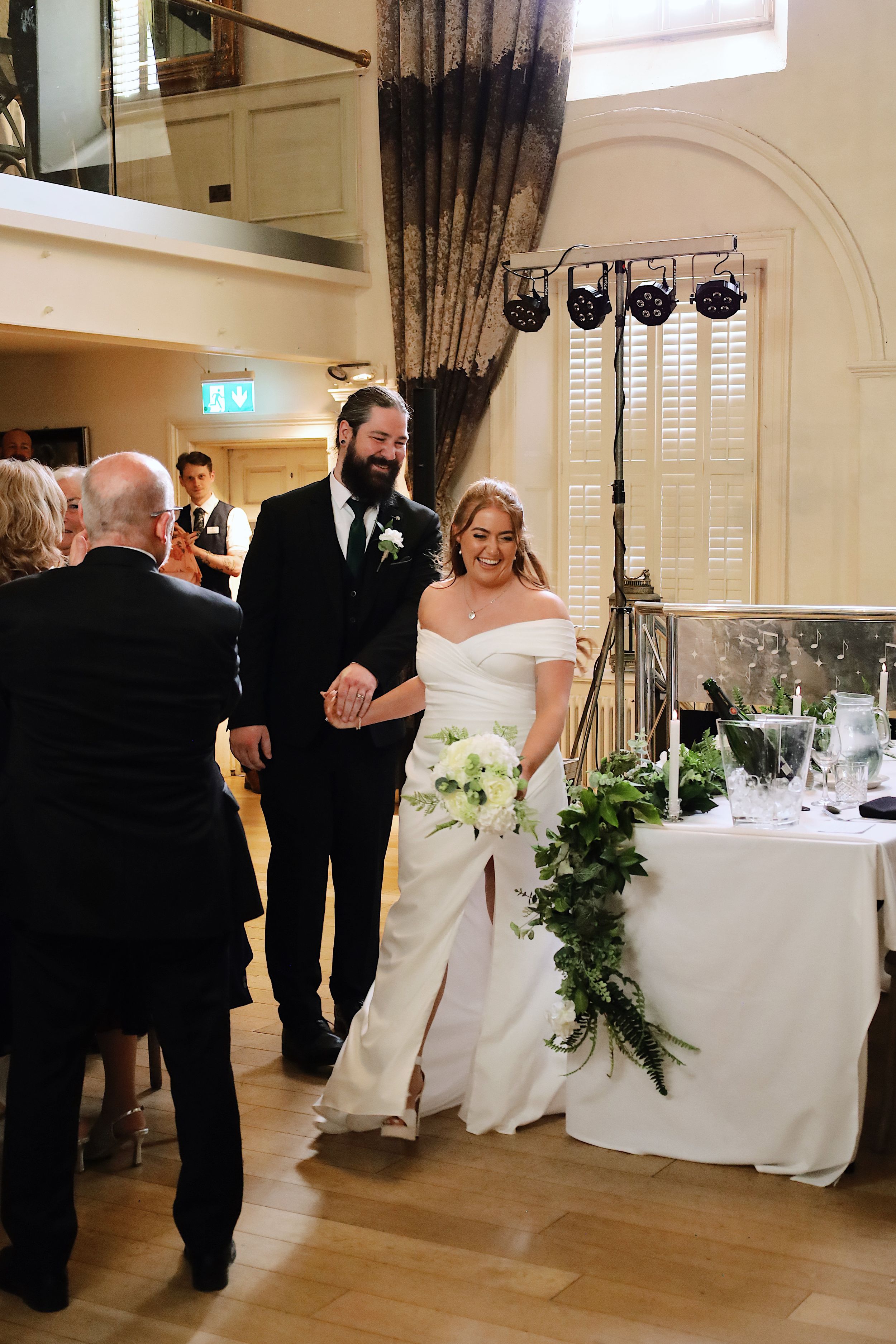 Wedding celebration scene in an elegant venue with decorated tables and hardwood floors.