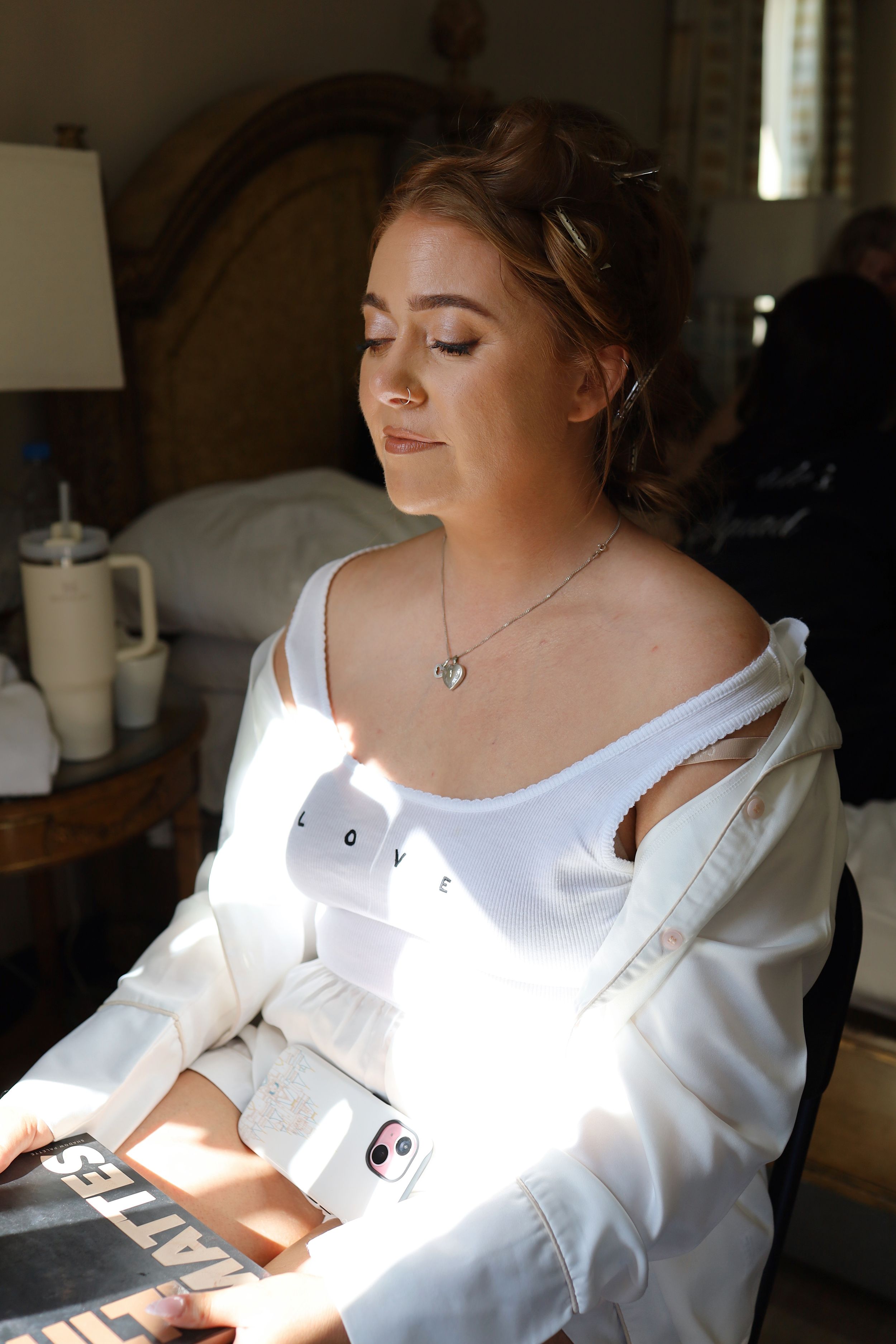 Sunlight streams through a window onto a person in a white dress during wedding preparations.