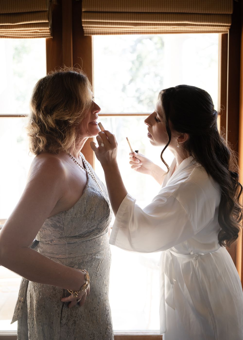 Two people in white dresses share an intimate dance together in a sunlit room.